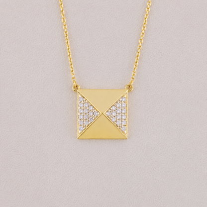 Gold necklace with a square pendant on a light gray background