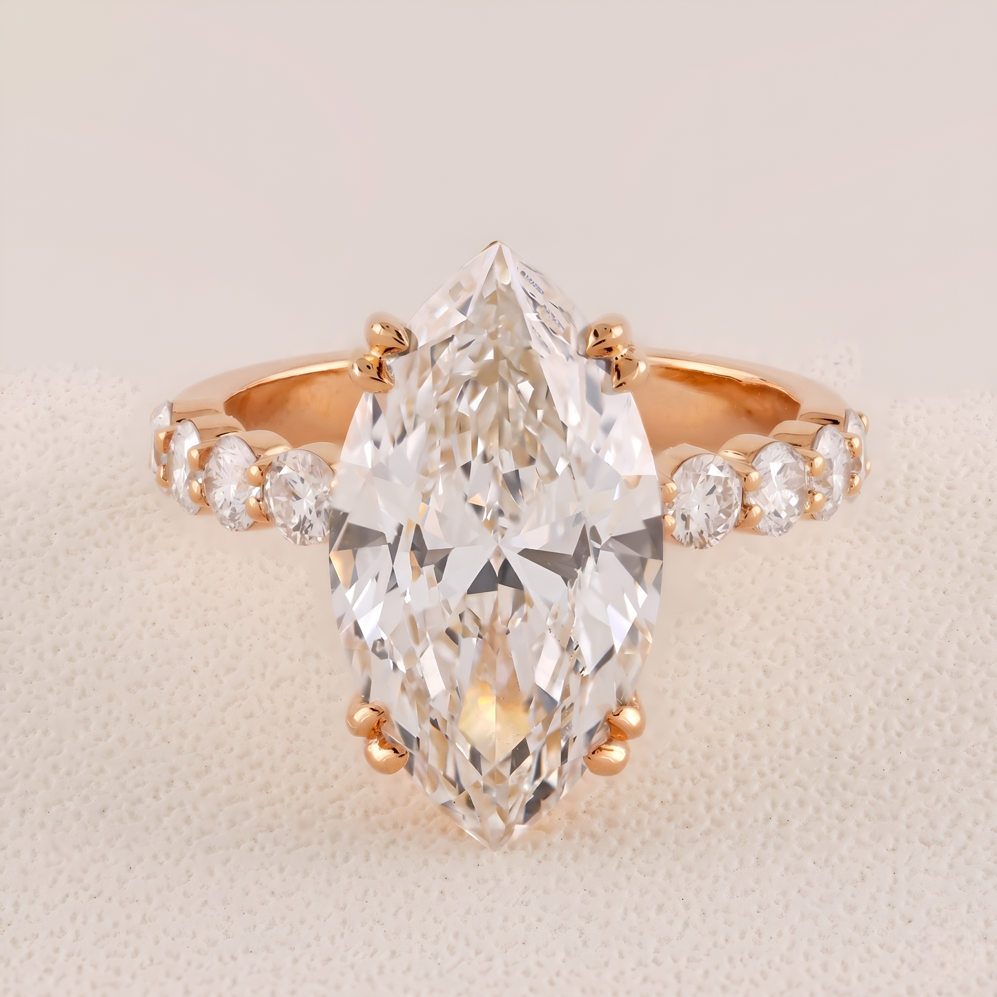 Rose gold ring with a large pear-shaped diamond and smaller diamonds on a beige background