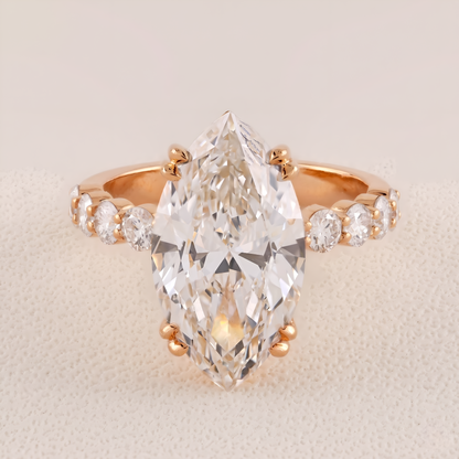 Rose gold ring with a large pear-shaped diamond and smaller diamonds on a beige background