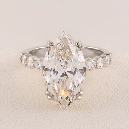 Diamond ring with a pear-shaped center stone on a light background