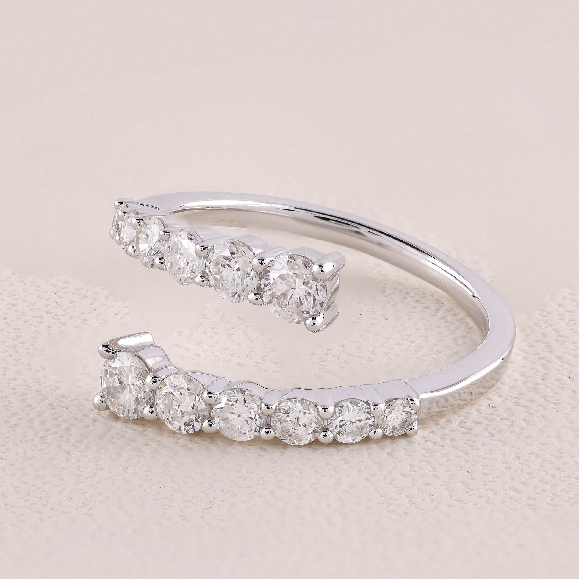 Silver open ring with embedded diamonds on a light beige background