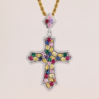 Jeweled cross pendant with colorful gemstones on a gold chain against a beige background