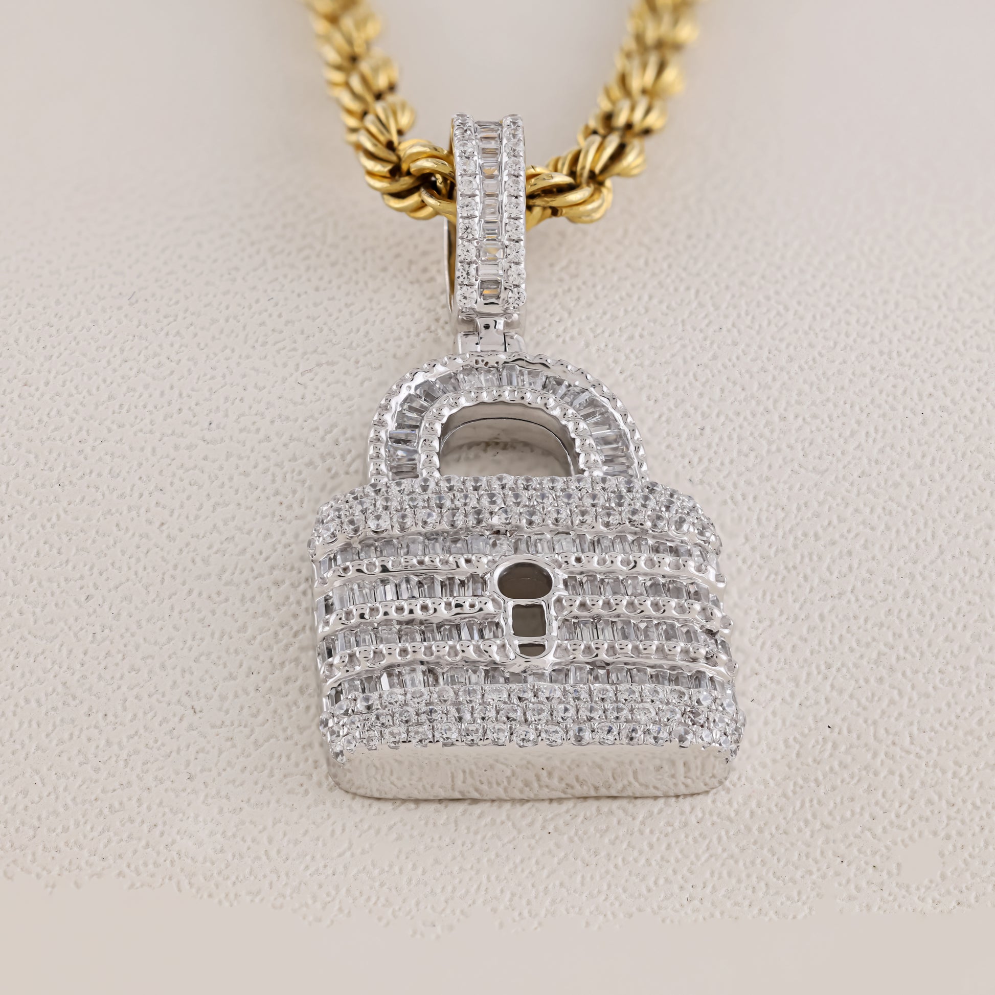 Diamond-encrusted lock-shaped pendant on a gold chain against a beige background