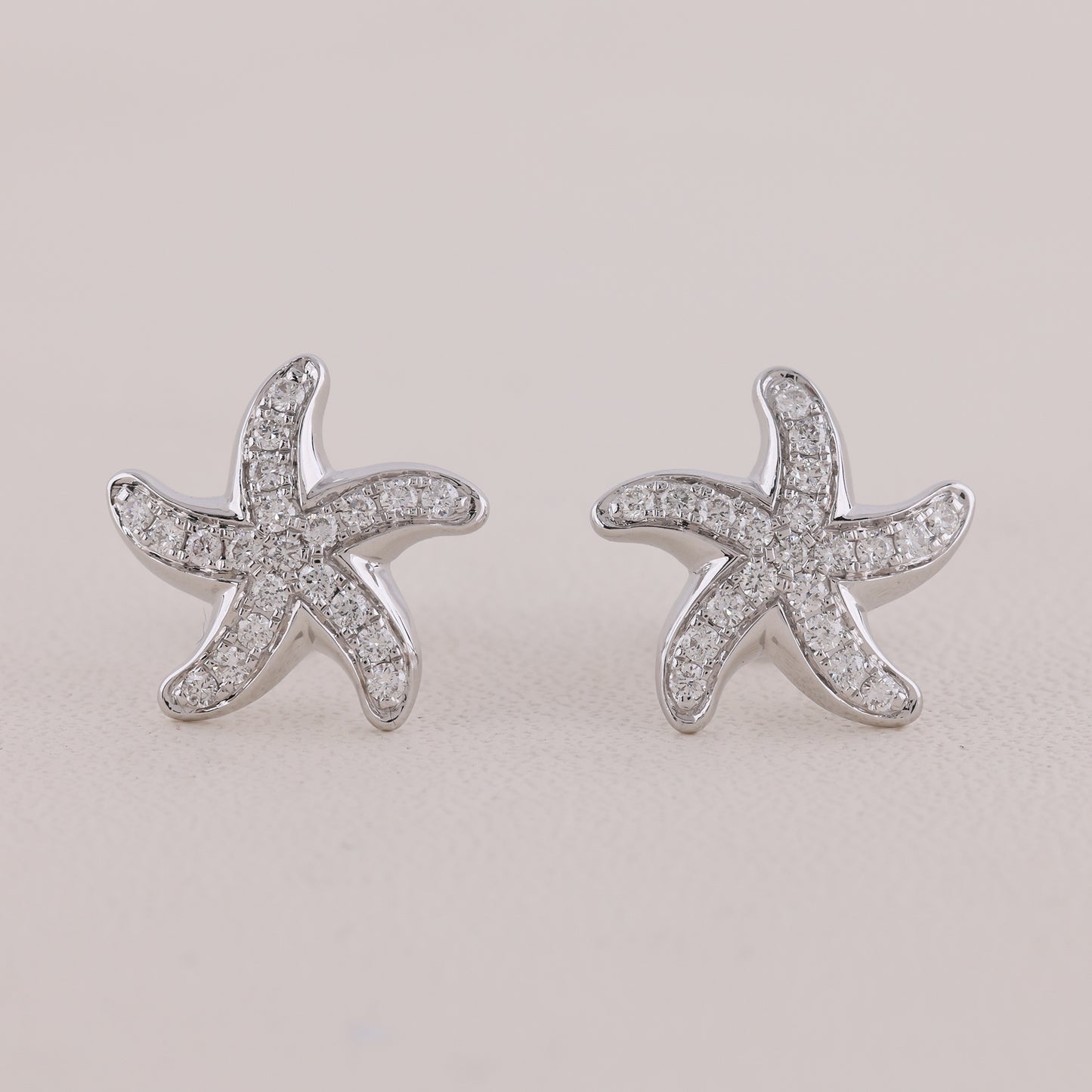 Starfish-shaped earrings with clear stones on a light gray background