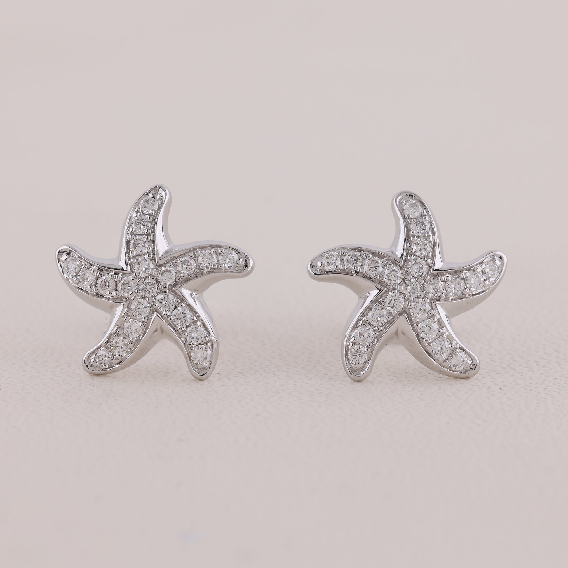 Starfish-shaped earrings with clear stones on a light gray background