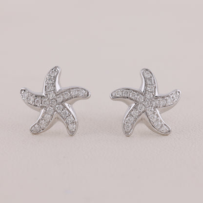 Starfish-shaped earrings with clear stones on a light gray background
