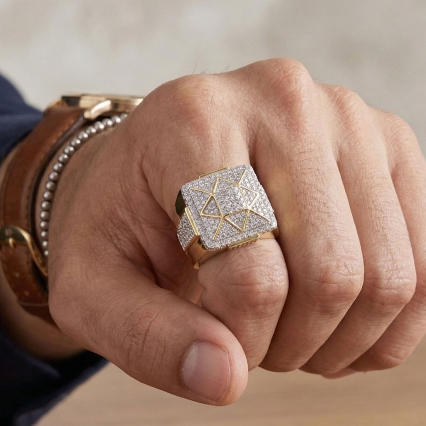 Hand wearing a gold ring with geometric design on a neutral background