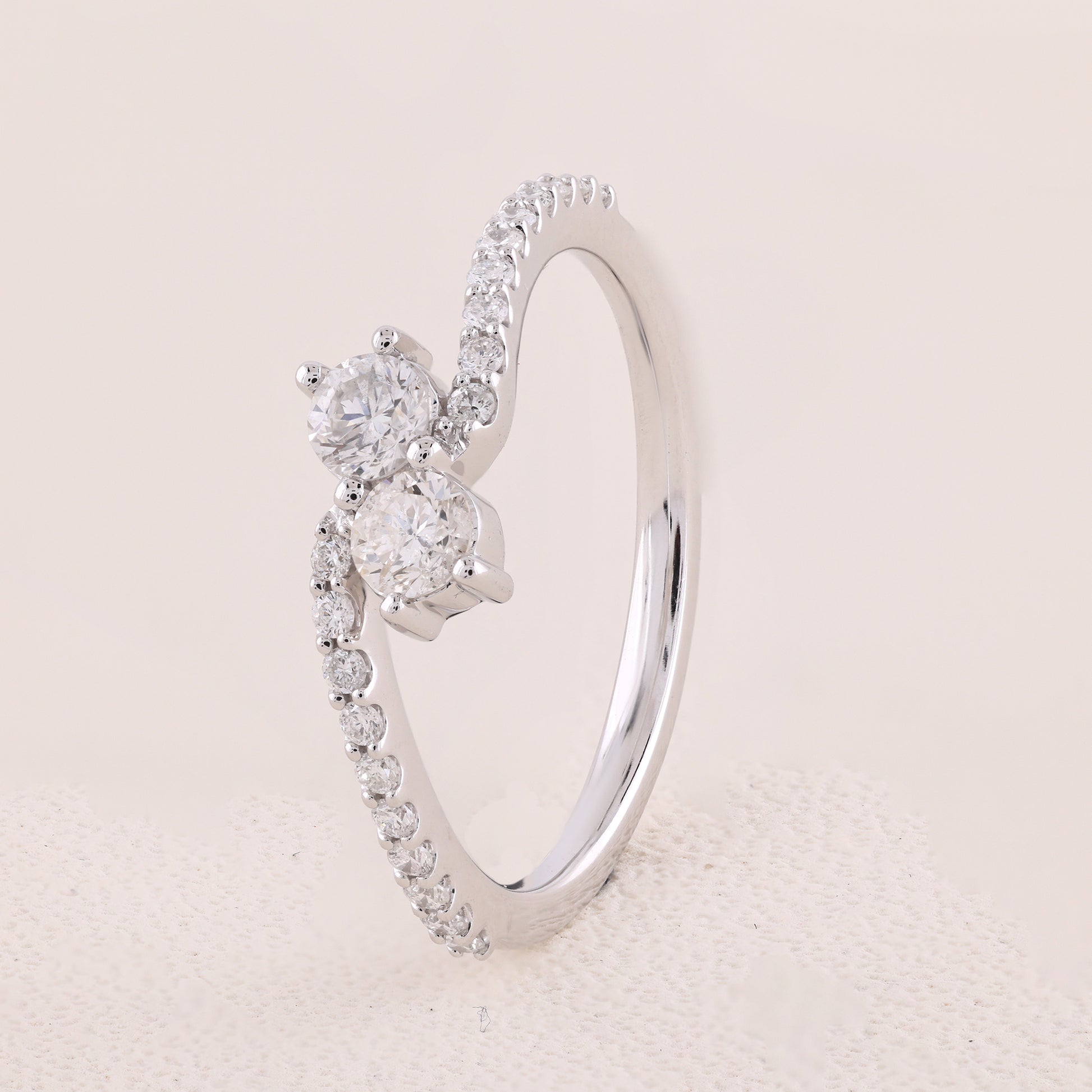 Silver ring with diamond accents on a light pink background