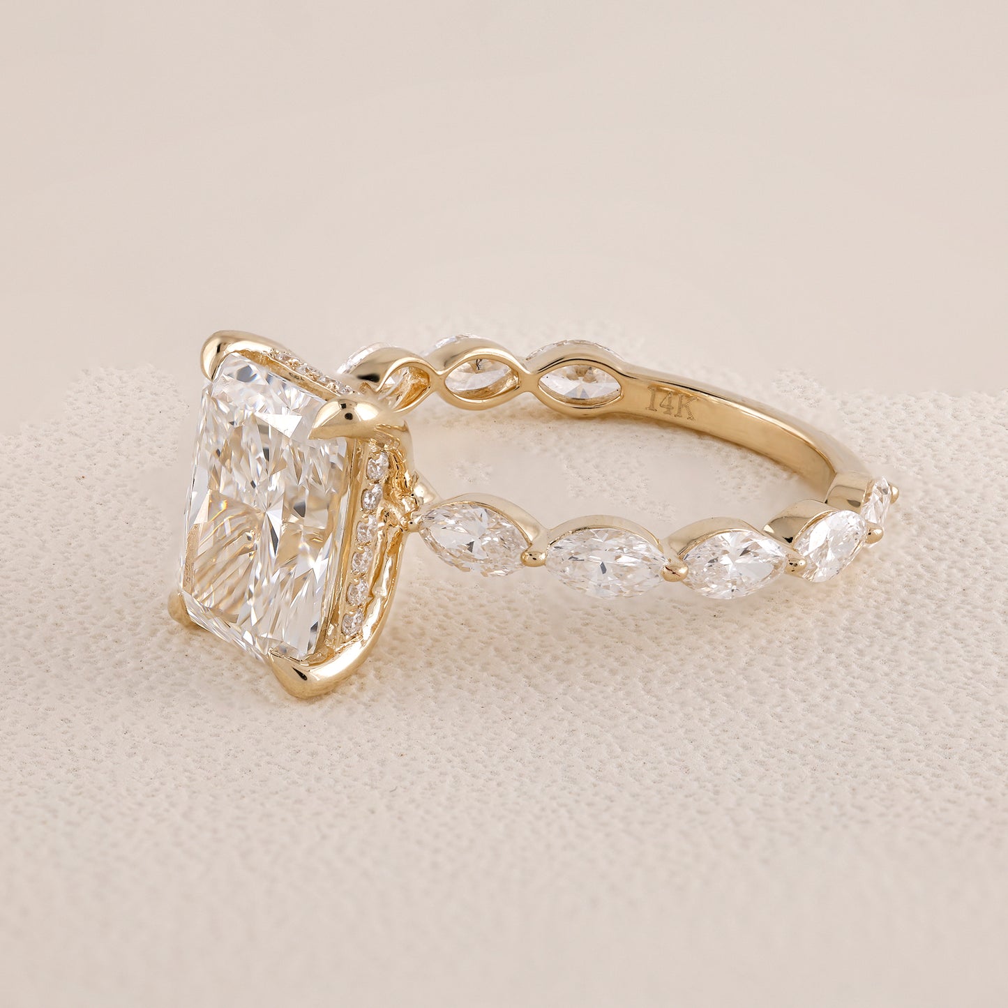 Gold ring with a large diamond and smaller stones on a beige background