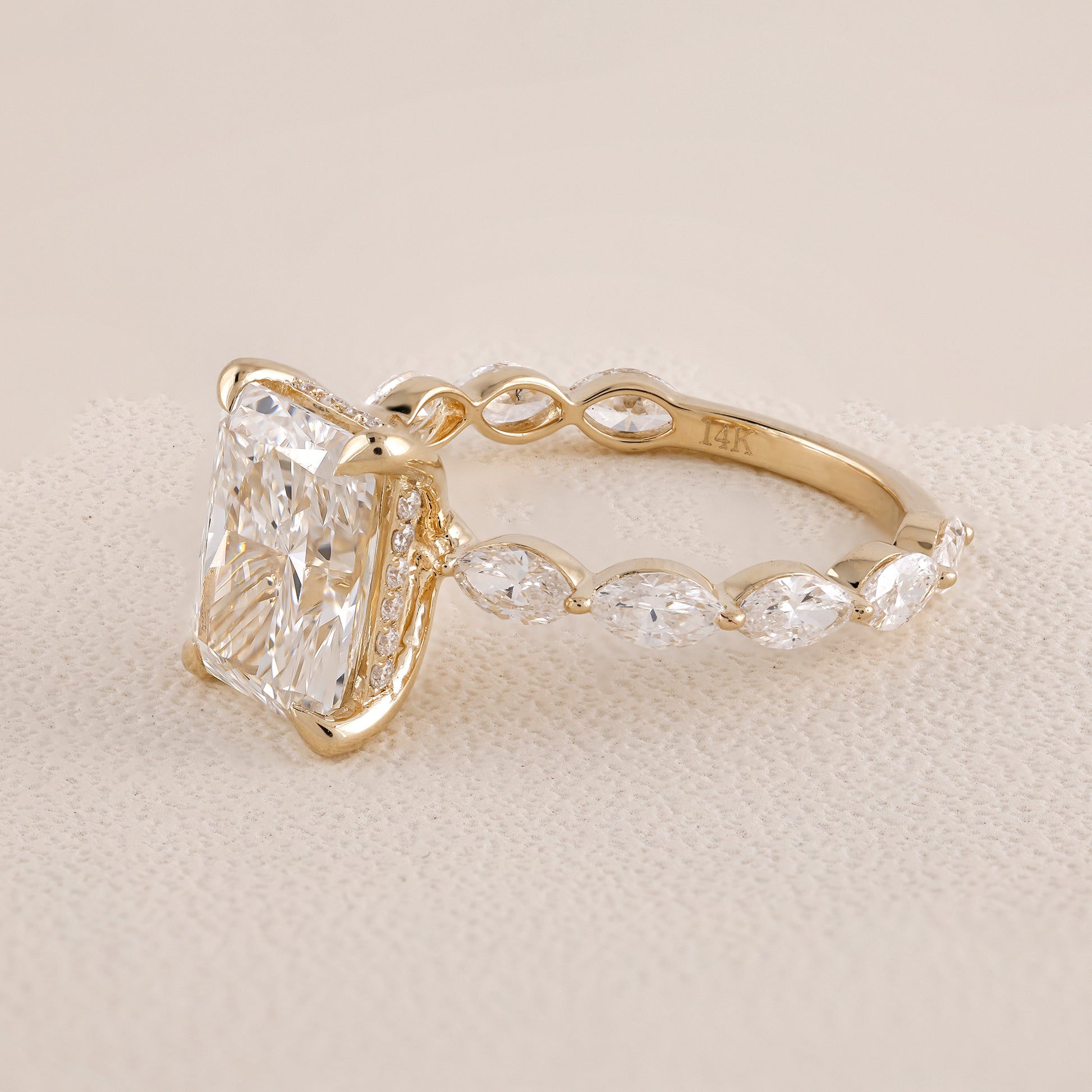 Gold ring with a large diamond and smaller stones on a beige background