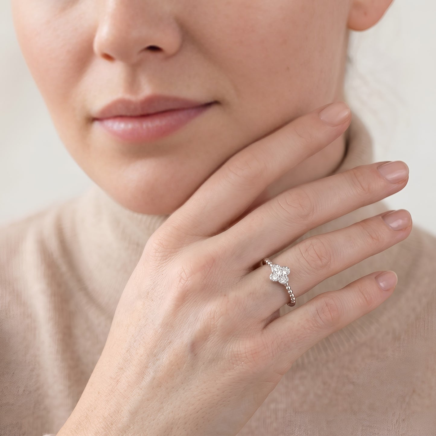 Close-up of a hand wearing a diamond ring with a neutral background