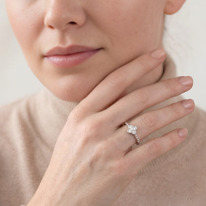 Close-up of a hand wearing a diamond ring with a neutral background