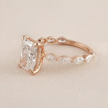 Rose gold ring with a large diamond and smaller stones on a beige background