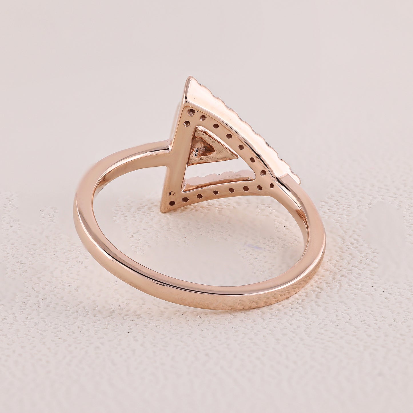 Rose gold ring with a triangular design on a light gray background