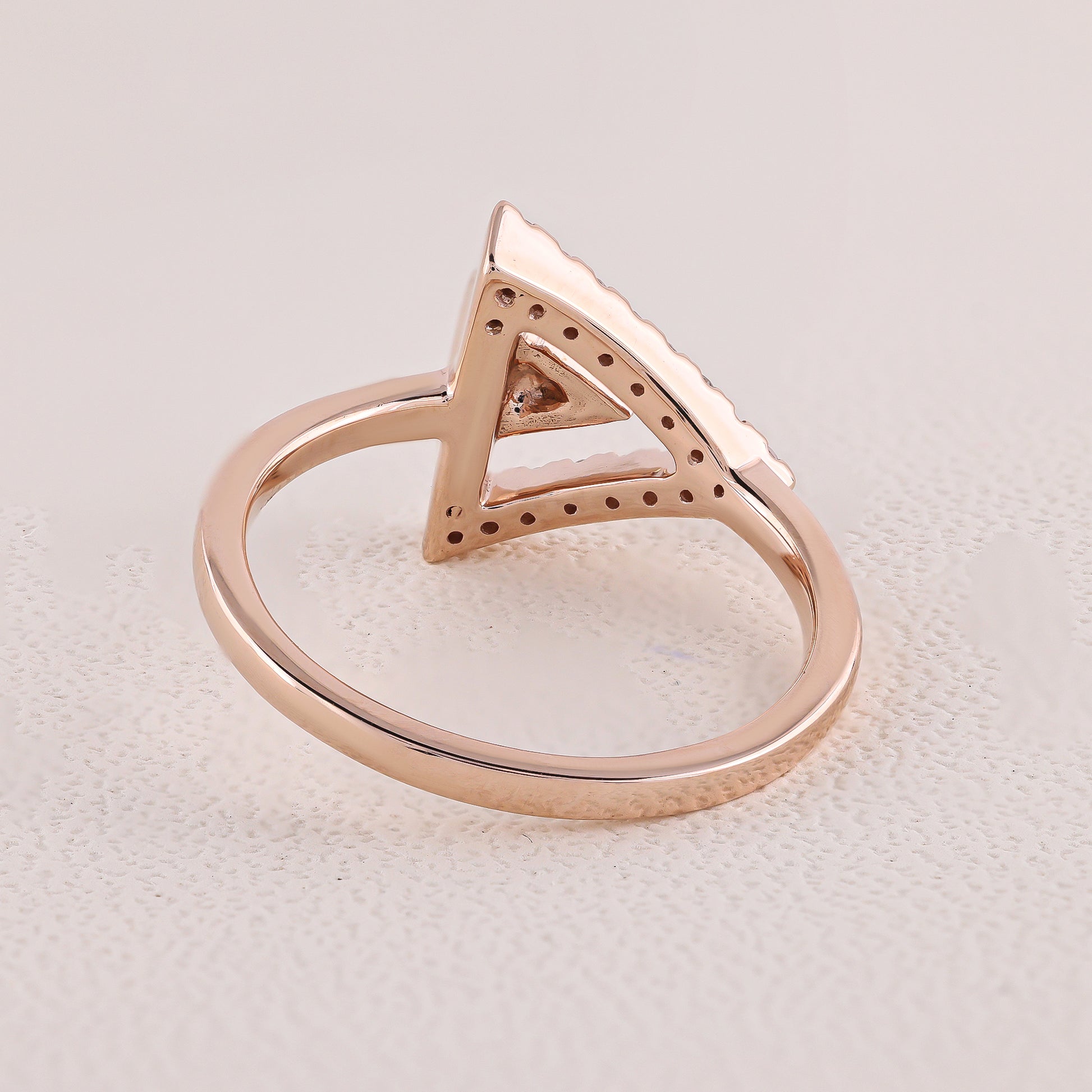 Rose gold ring with a triangular design on a light gray background
