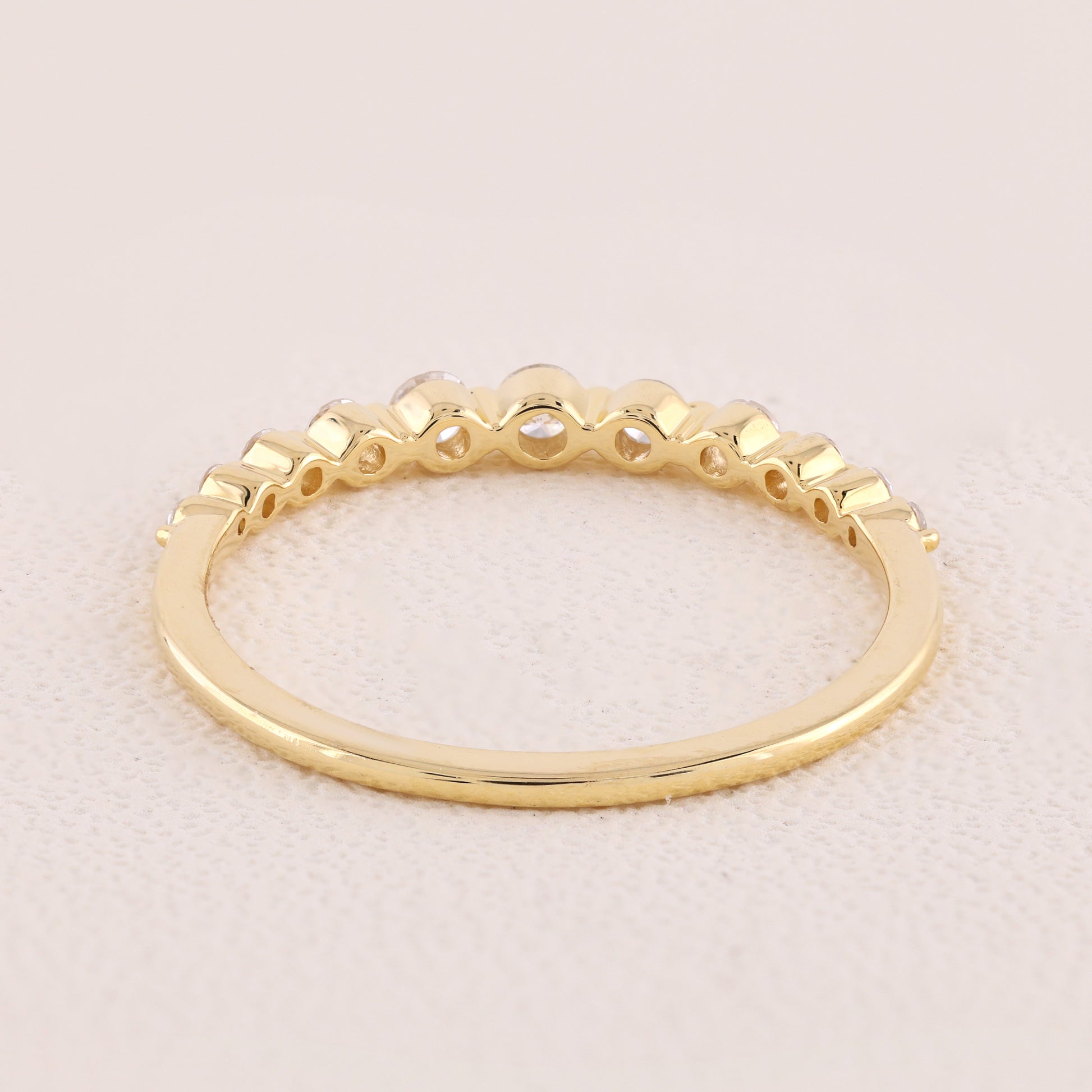 Gold ring with a textured band on a light pink background