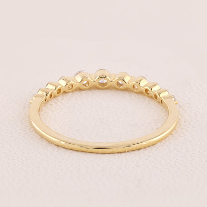 Gold ring with a textured band on a light pink background