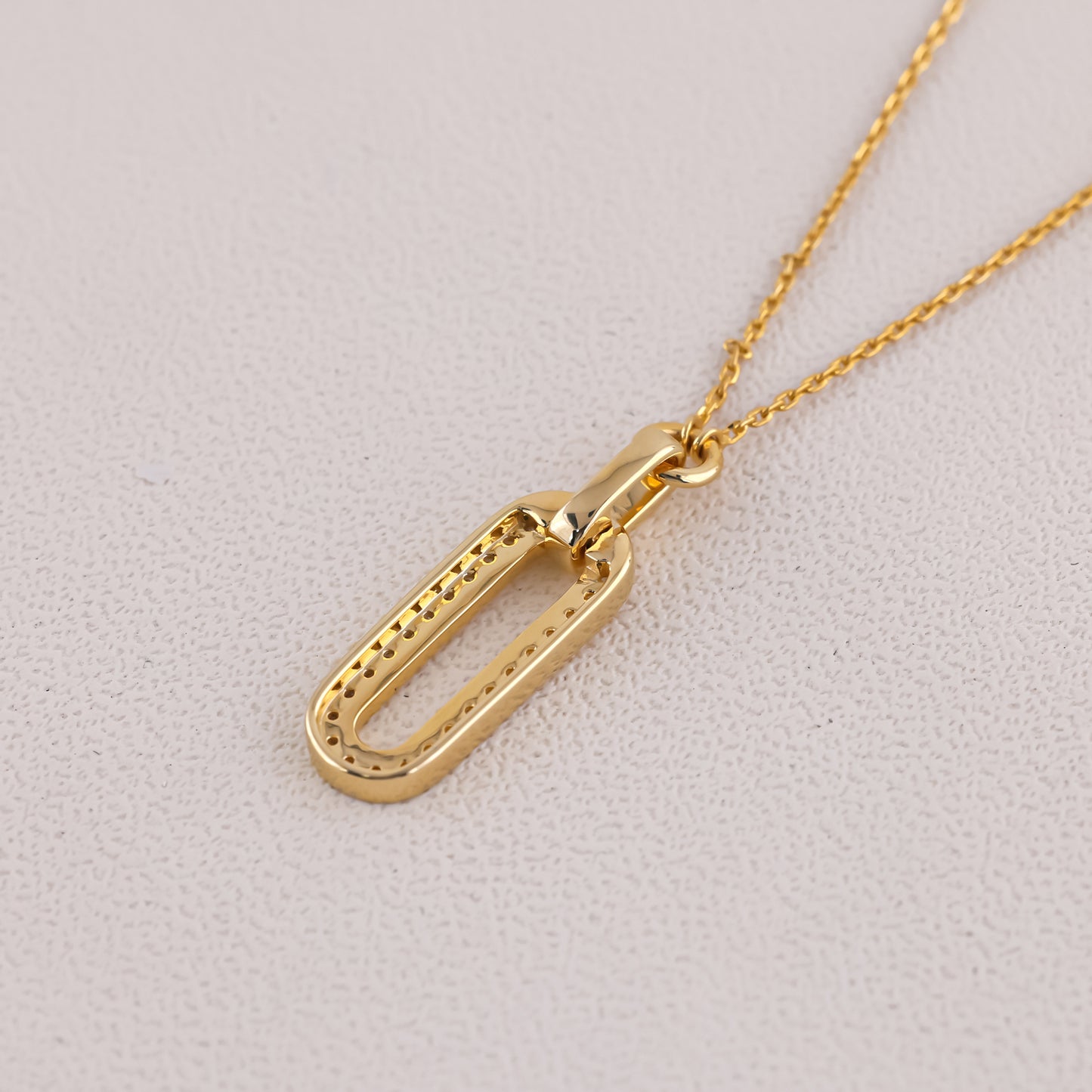 Gold necklace with a unique pendant on a light gray background