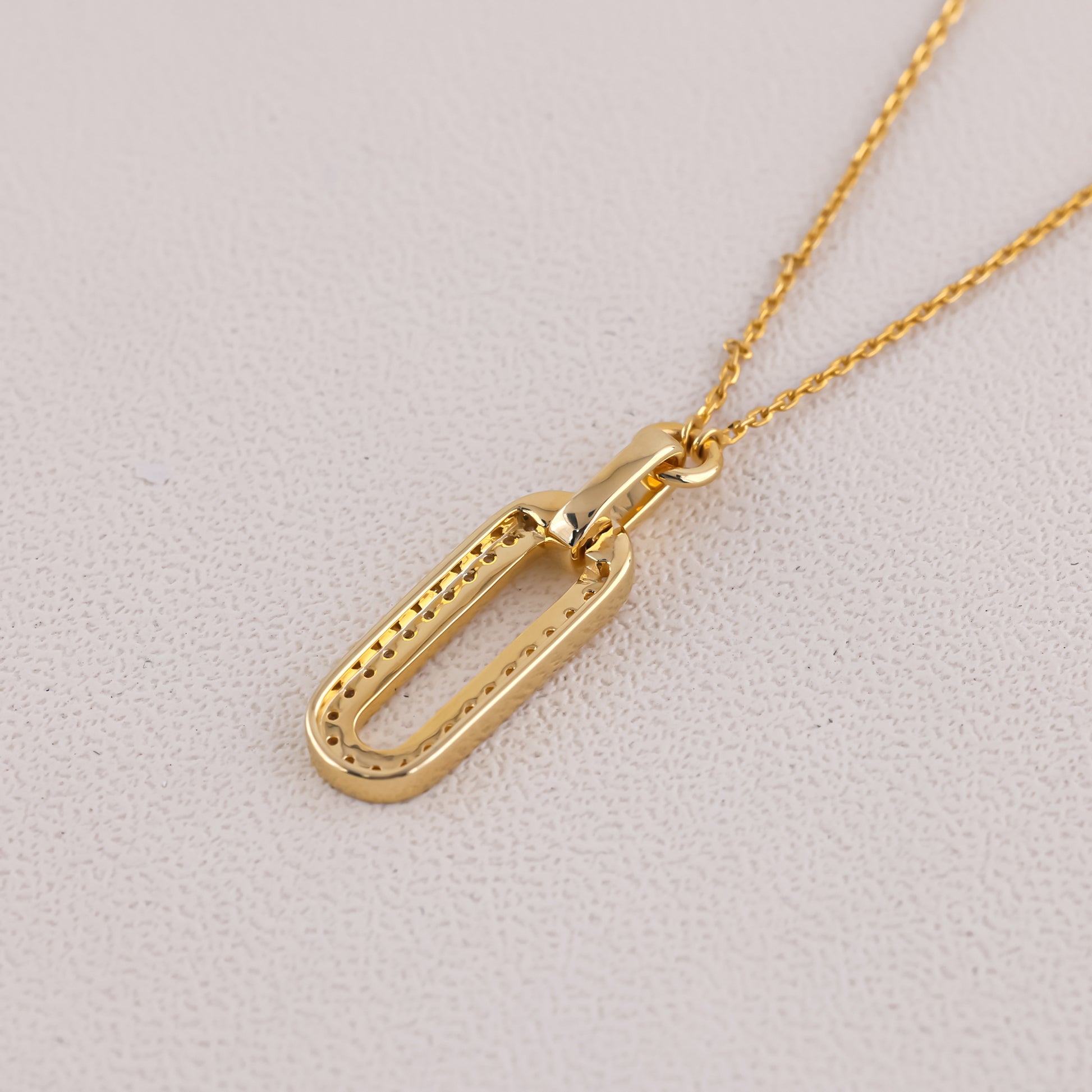 Gold necklace with a unique pendant on a light gray background