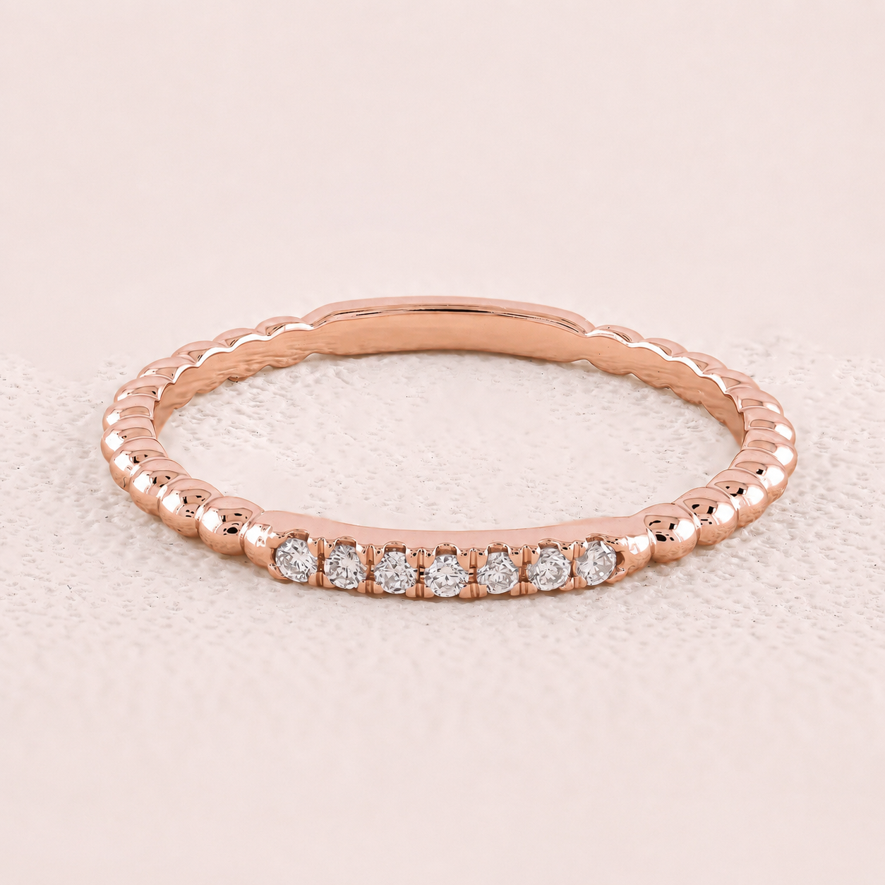 Rose gold ring with diamonds on a light beige background