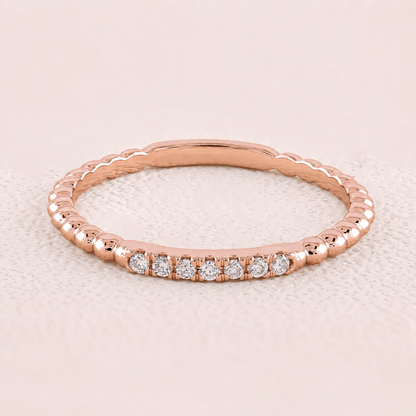 Rose gold ring with diamonds on a light beige background