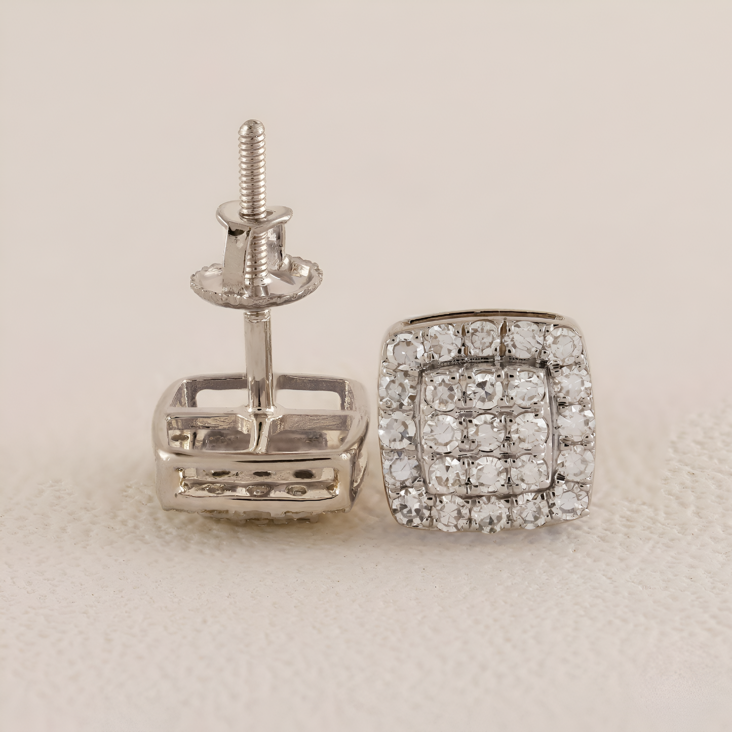 Silver square-shaped earrings with clear gemstones on a light beige background