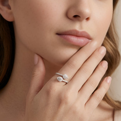Close-up of a woman's hand wearing a silver ring with a diamond, touching her chin.