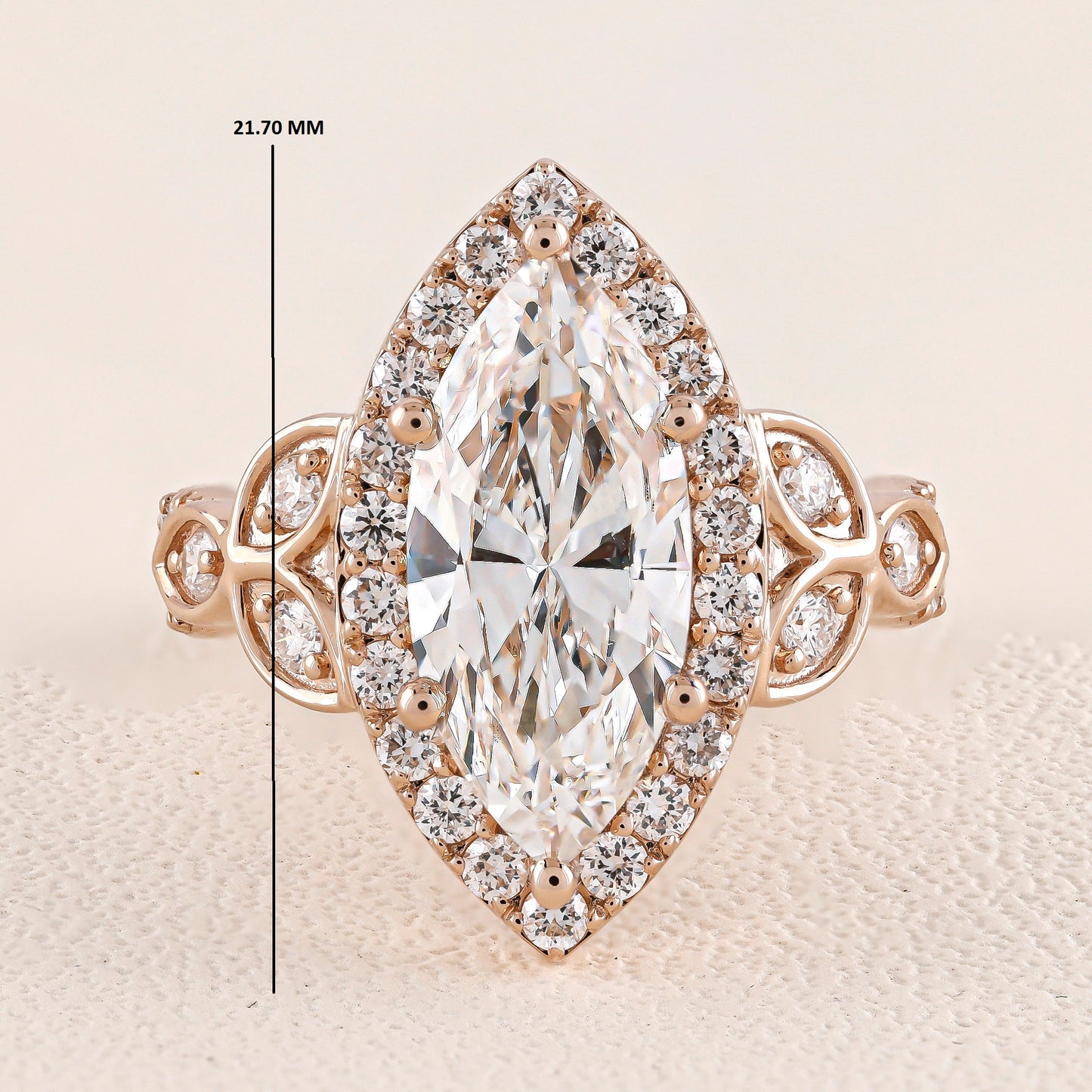 Rose gold ring with a large diamond and smaller diamonds around on a beige background