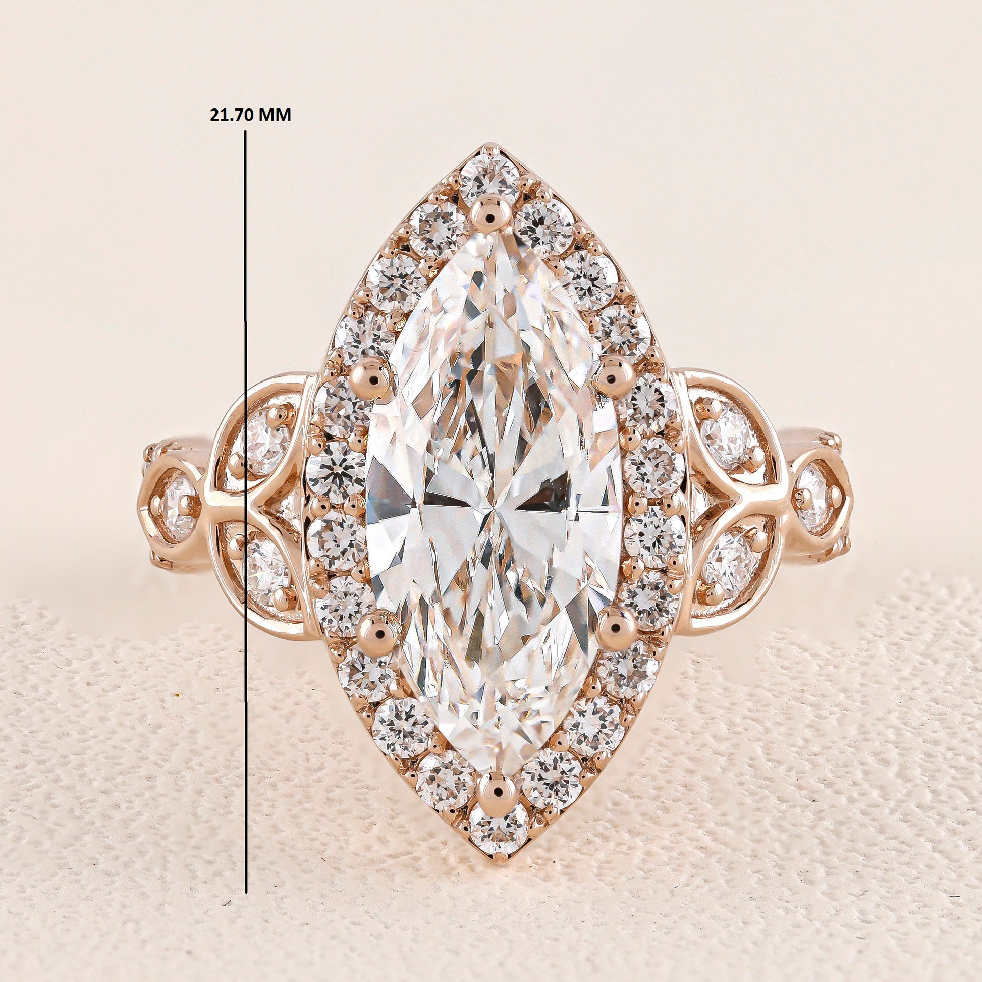 Rose gold ring with a large diamond and smaller diamonds around on a beige background