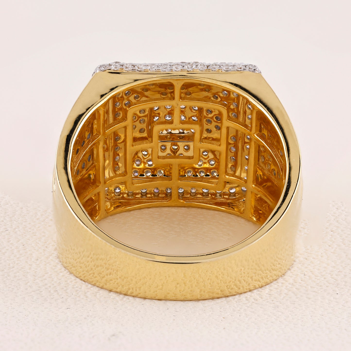 Gold ring with intricate design and small diamonds on a light background