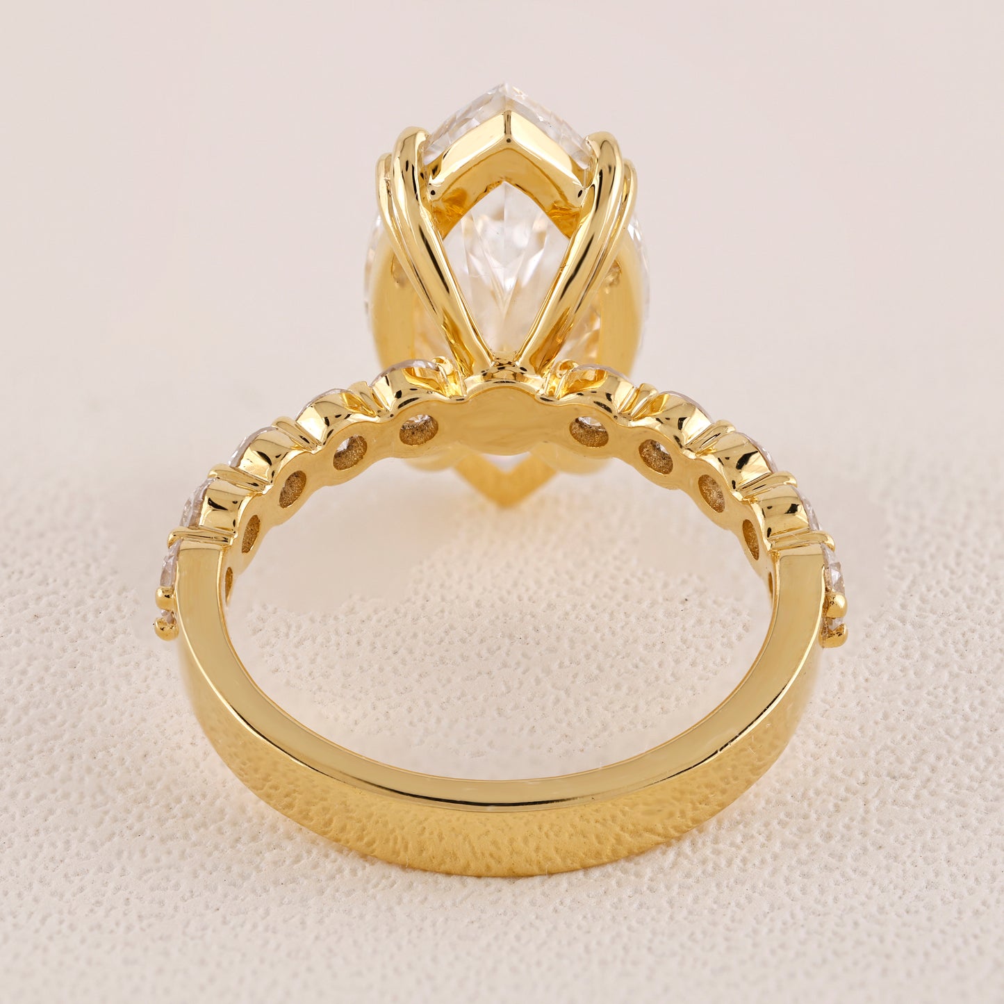 Gold ring with a prominent diamond on a beige background