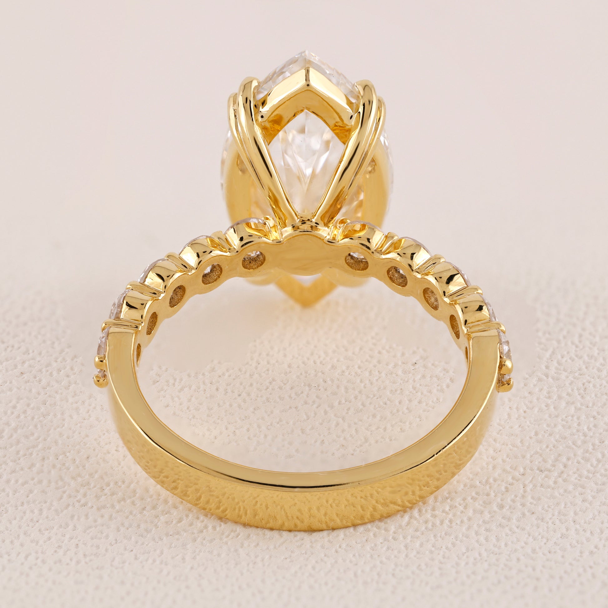 Gold ring with a prominent diamond on a beige background