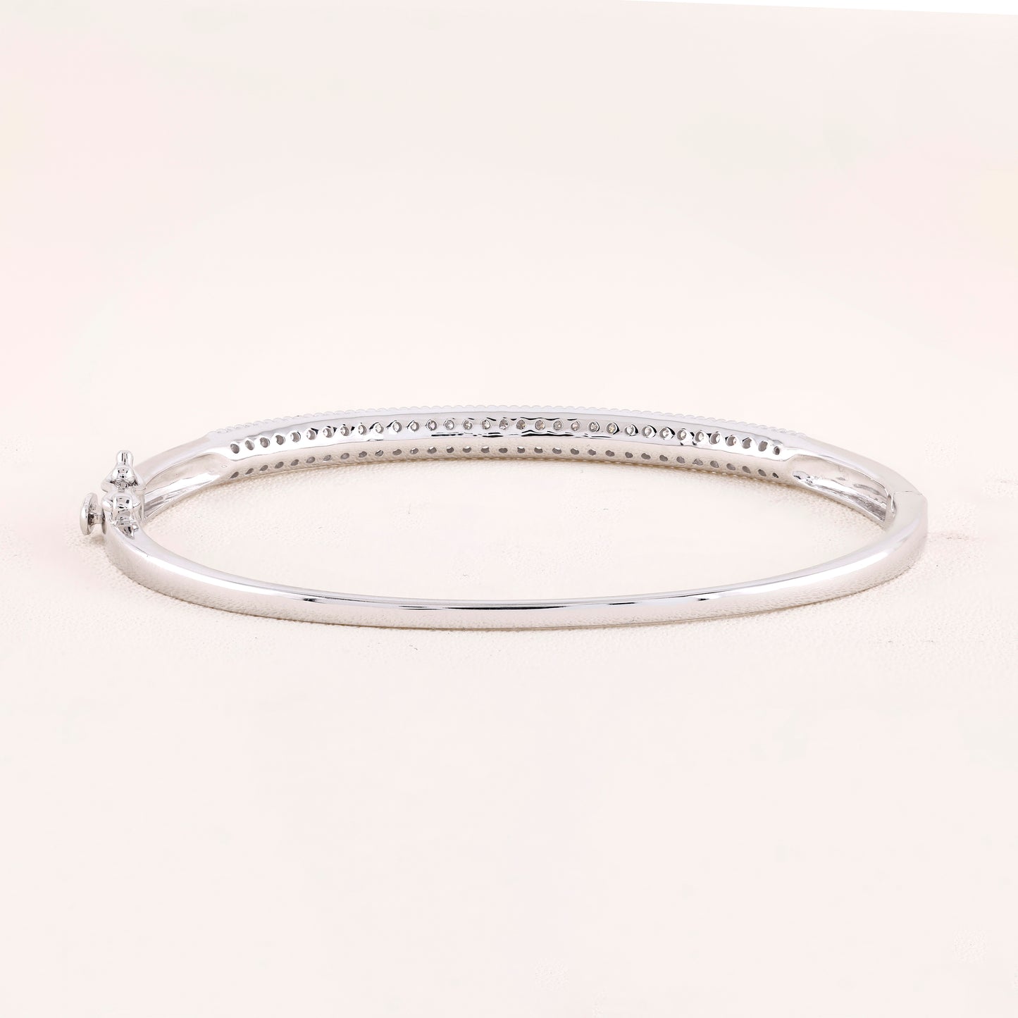 Silver bangle on a light pink background