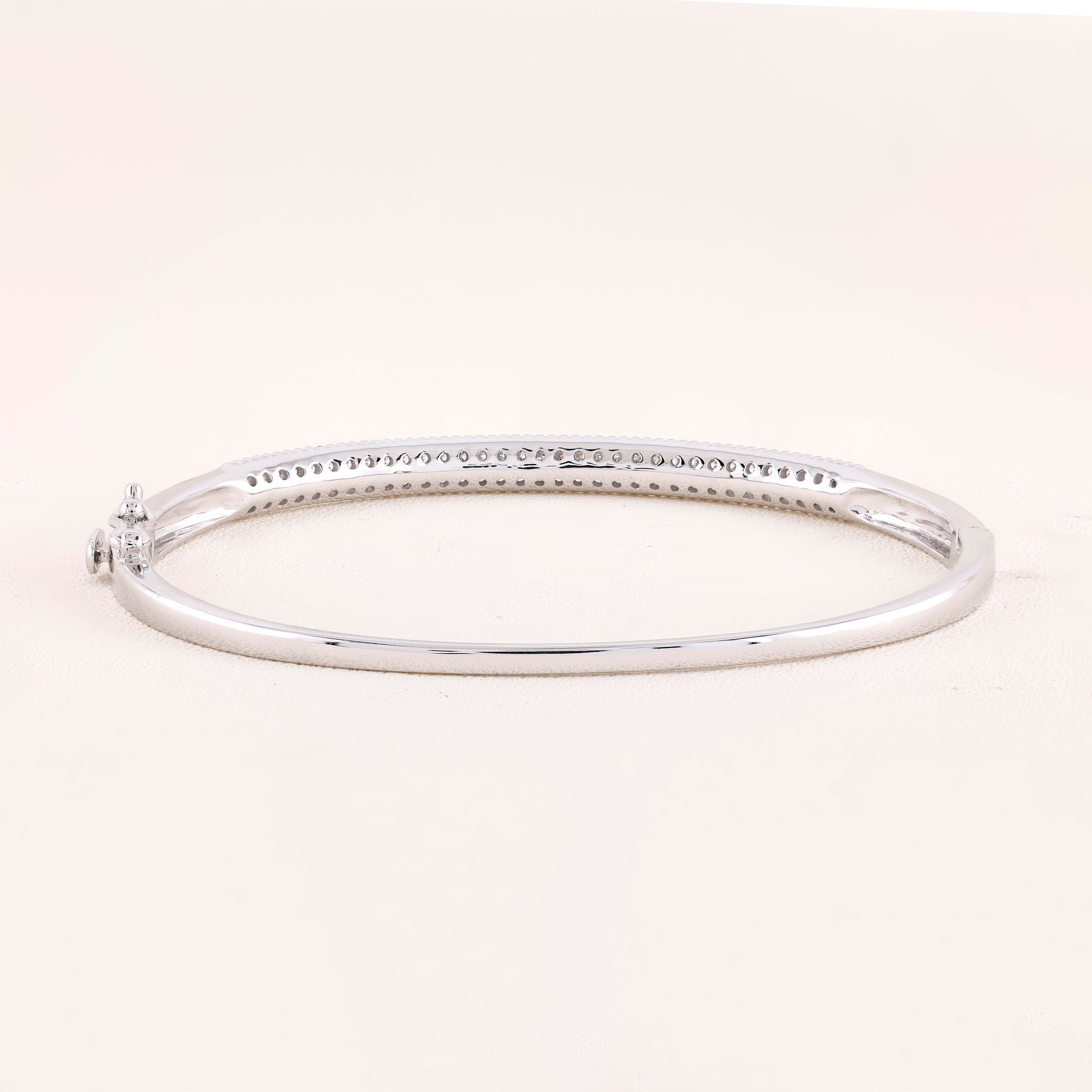 Silver bangle on a light pink background