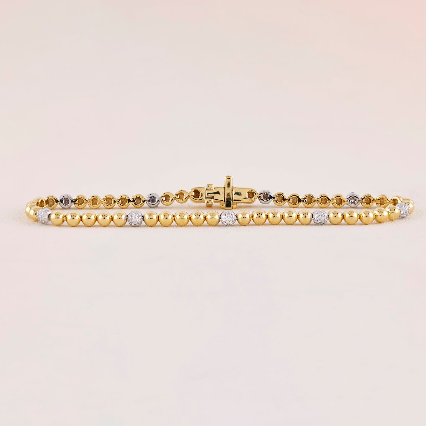 Gold bracelet with embedded diamonds on a light beige background