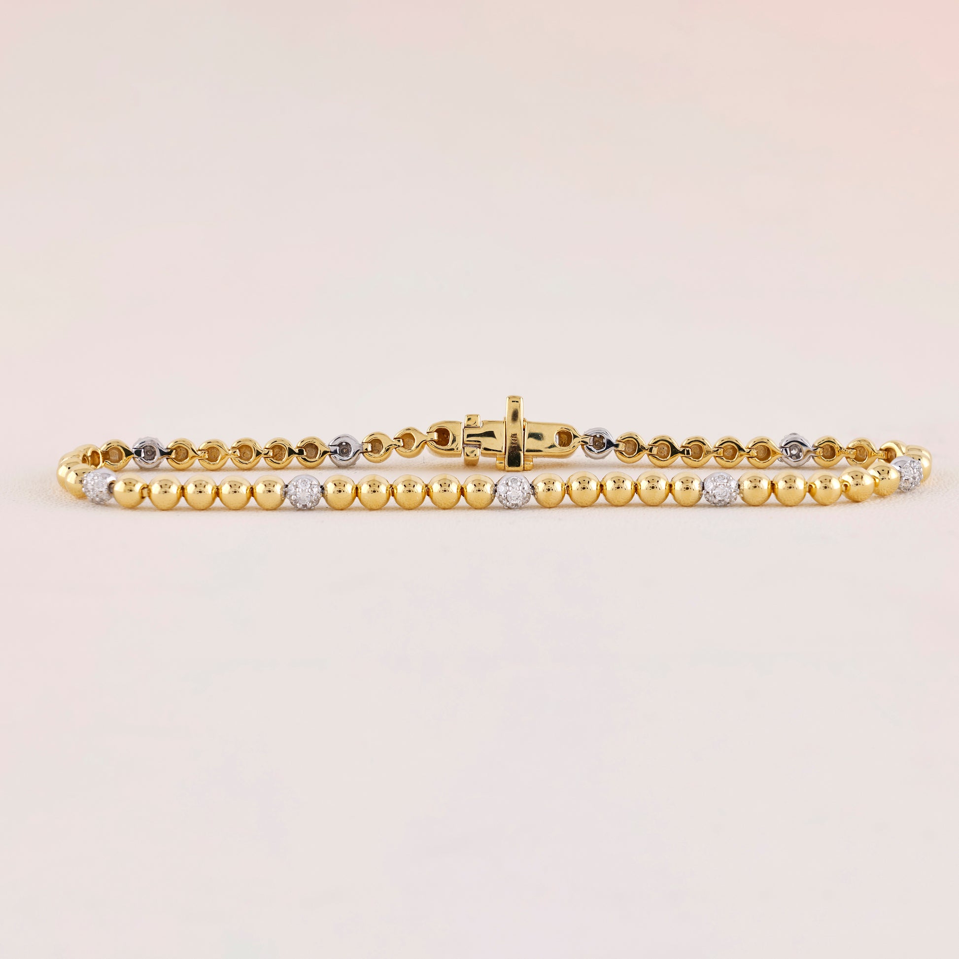 Gold bracelet with embedded diamonds on a light beige background