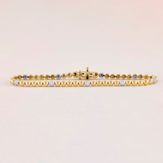 Gold bracelet with embedded diamonds on a light beige background