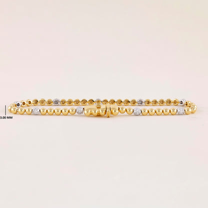 Gold bracelet with small beads on a light beige background