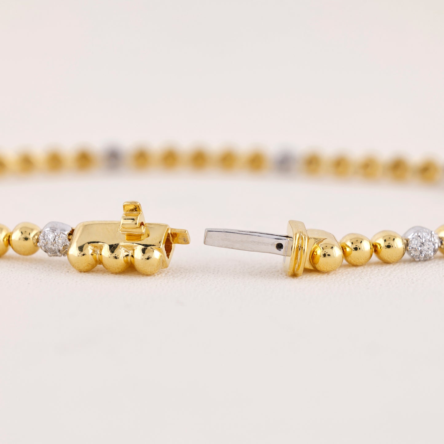 Close-up of gold beaded bracelets with diamond accents on a light background