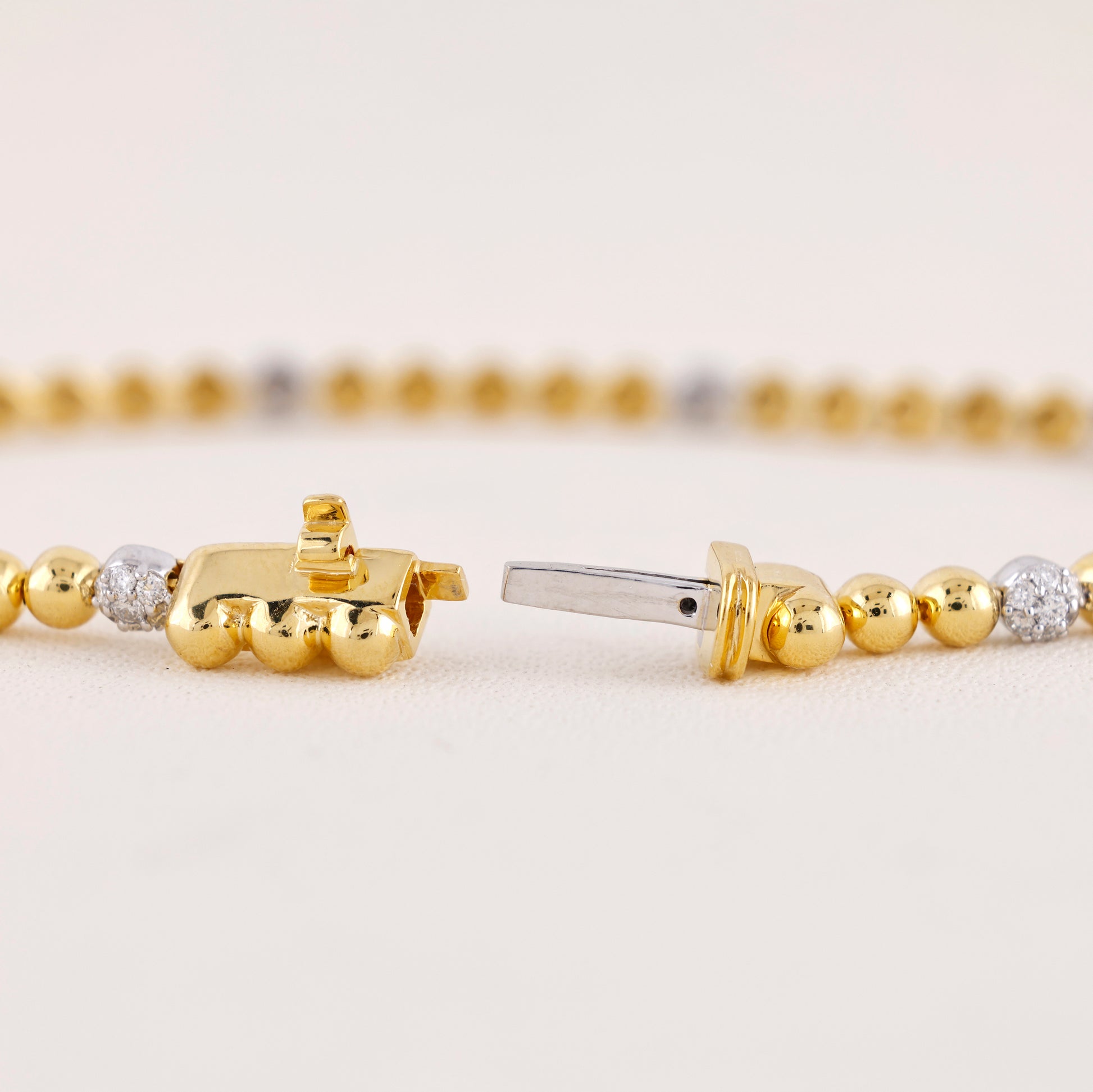 Close-up of gold beaded bracelets with diamond accents on a light background