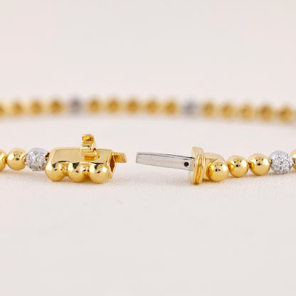 Close-up of gold beaded bracelets with diamond accents on a light background