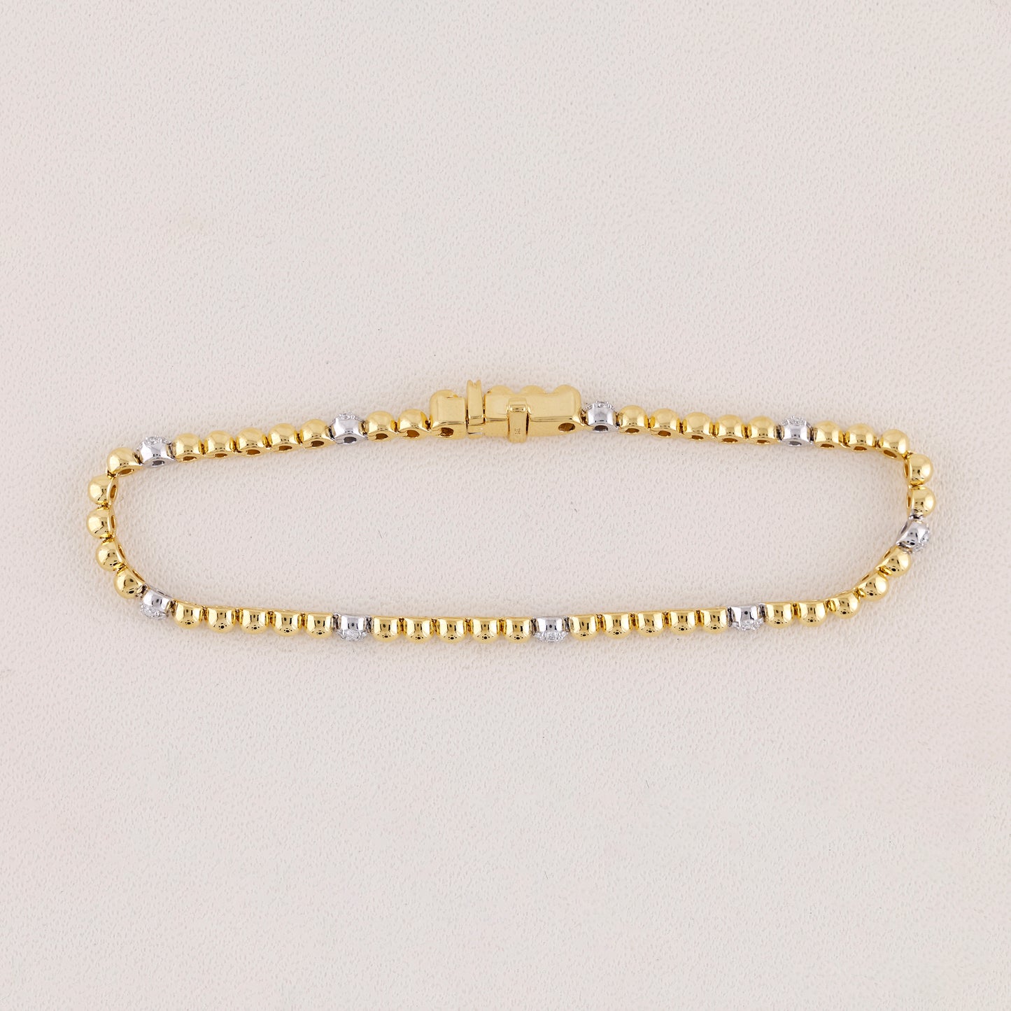 Gold and silver beaded bracelet on a light beige background