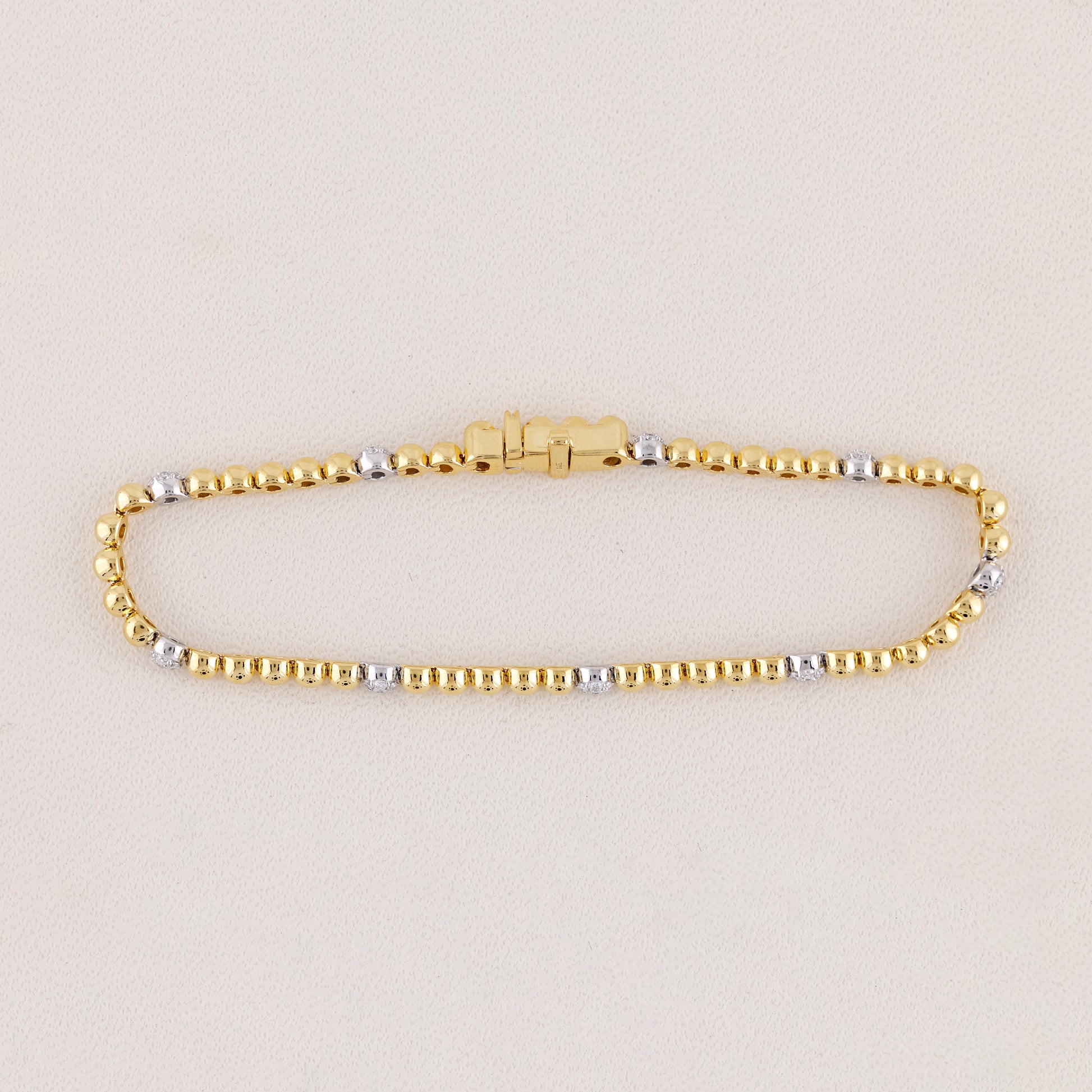 Gold and silver beaded bracelet on a light beige background