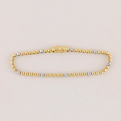 Gold and silver beaded bracelet on a light beige background