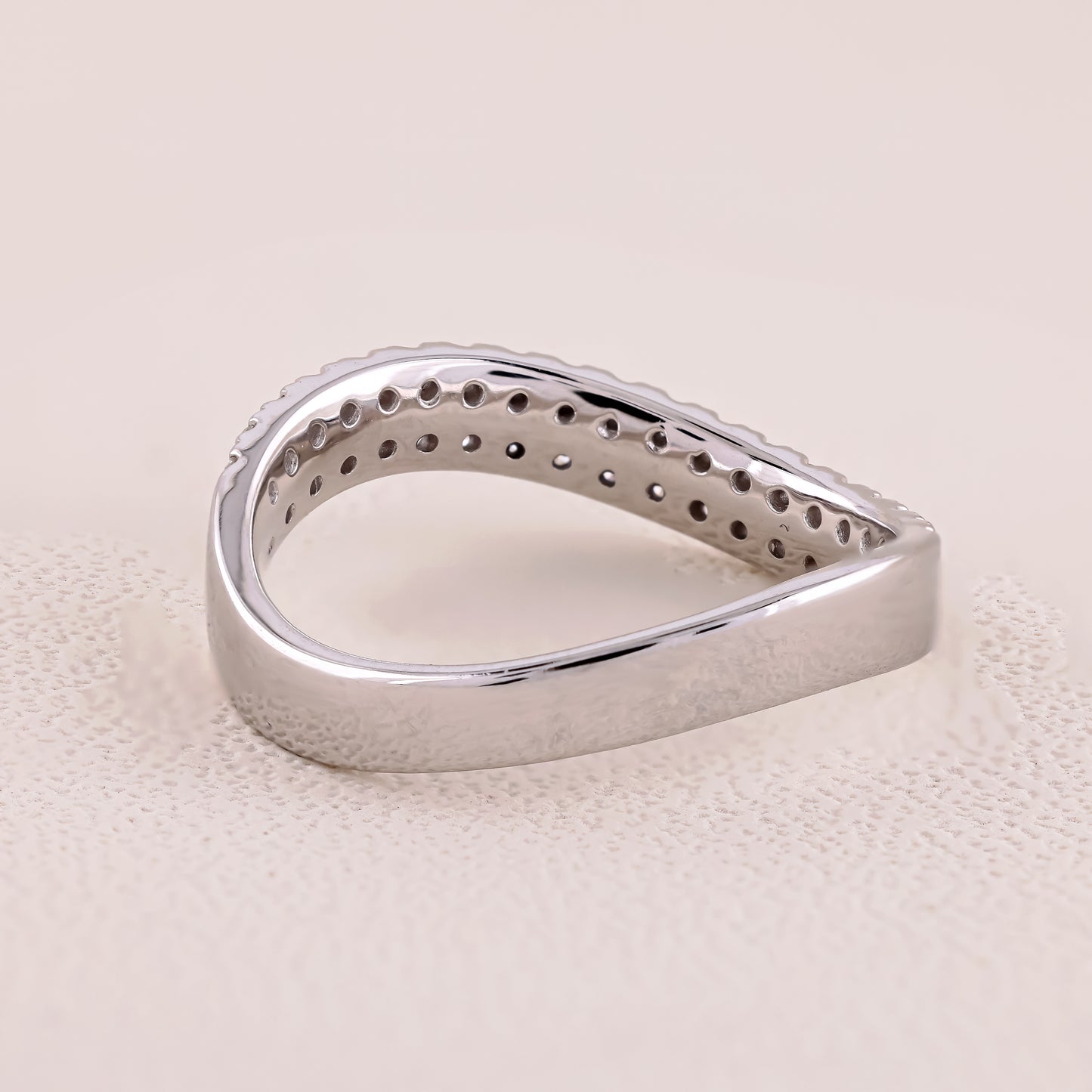 Silver ring with a textured surface on a beige background