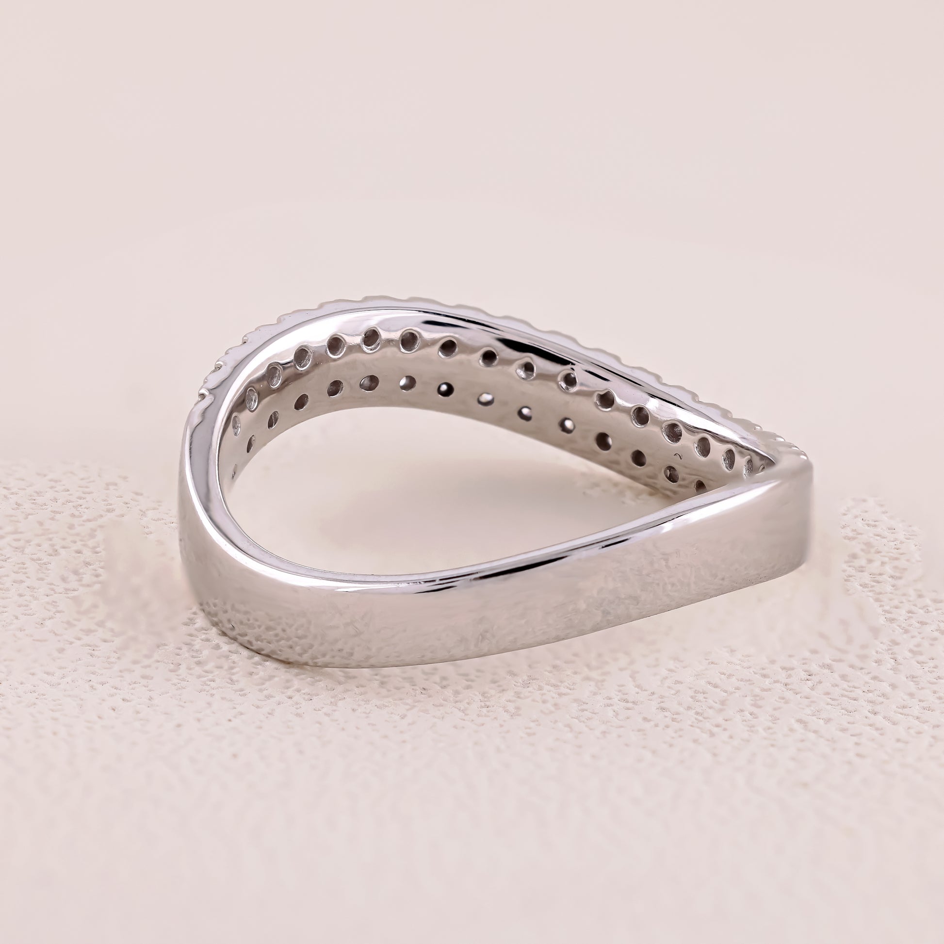 Silver ring with a textured surface on a beige background