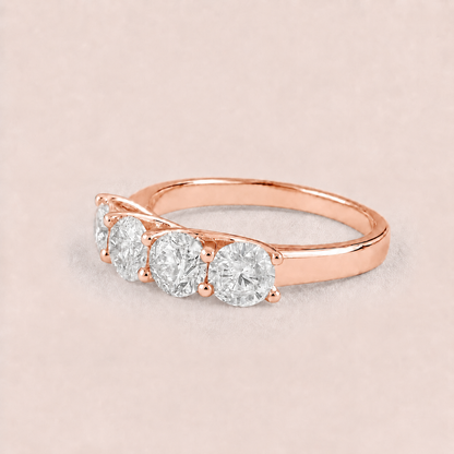 A rose gold three-stone diamond ring with round-cut diamonds set in a polished band, displayed on a soft beige background.