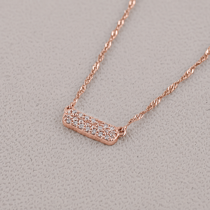 Rose gold necklace with a diamond pendant on a light gray background