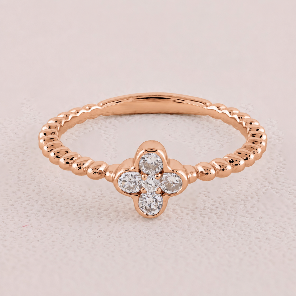 Rose gold ring with diamond flower design on a light pink background
