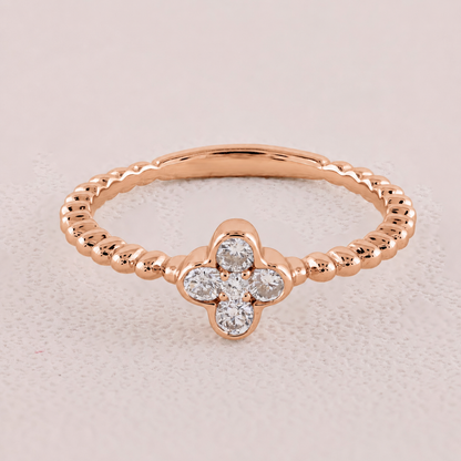 Rose gold ring with diamond flower design on a light pink background